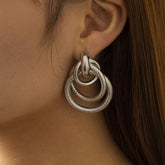 A close-up image of a person's ear wearing a silver-plated layered circle drop earring.
